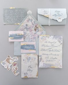 the wedding stationery is laid out on top of each other, including envelopes and cards