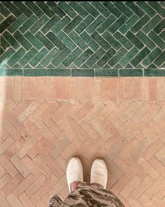 a person standing in front of a tiled floor with their feet up on the ground