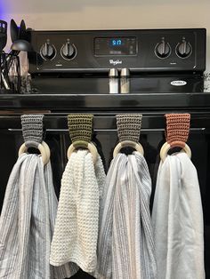 three kitchen towels hanging on the front of an oven with knobs and rings attached to them