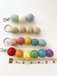 felt balls and measuring tape on white surface with ruler in foreground, used for keychains