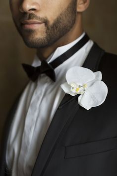 a man in a tuxedo with a white flower on his lapel collar