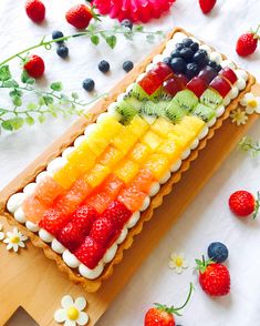 an image of a cake made to look like a rainbow fruit tart on a wooden platter