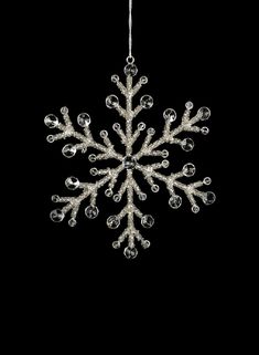 a snowflake ornament hanging from a string on a black background in the shape of a snowflake