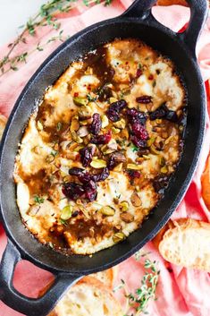 an iron skillet filled with baked bread and cranberry sauce on a pink cloth