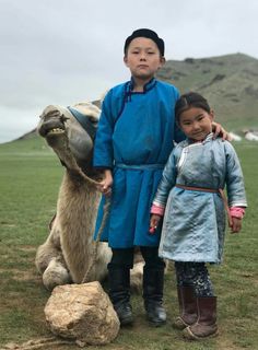 two young children standing next to an animal