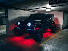 a jeep parked in a parking garage with red lights on the front and back tires