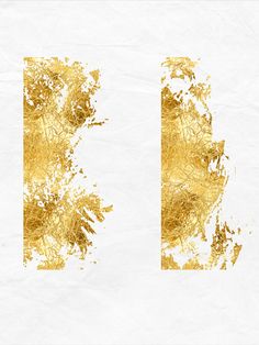 gold paint splattered on white paper with the letter d in it's center