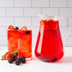 two pitchers of red liquid with strawberries and blackberries next to eachother