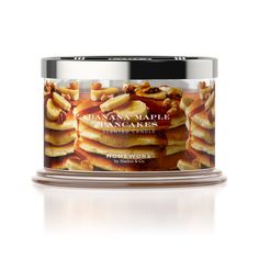 banana maple pancakes in a glass jar on a white surface with a silver lid and wooden base