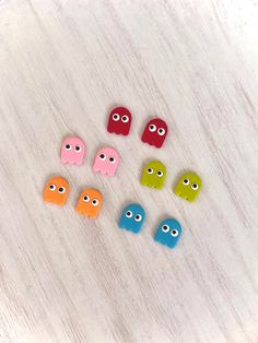 six different colored buttons with eyes on white wood background, close up view from above