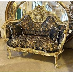 an ornate gold and black couch in front of a mirror