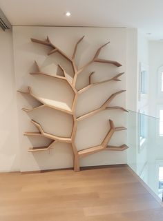 a large wooden tree is in the middle of a room with white walls and wood flooring