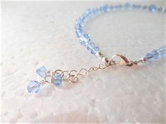 "This Crystal ankle bracelet is the perfect Something Blue for the Bride or for that dazzling finishing touch to any outfit. Get your sparkle on with light blue premium quality crystals that sparkle and shimmer around your ankle, sure to dazzle all who see it. The sterling silver clasp and chain make it adjustable for a comfortable fit and ends in a flirty crystal dangle. The pictured anklet will fit an ankle 9\" to 10\" depending on where you want it to sit (9\" is considered average size for w Elegant Blue Anklets For Gifts, Elegant Blue Anklets For Gift, Adjustable Blue Crystal Bracelet With Lobster Clasp, Blue Crystal Bracelet With Lobster Clasp And Adjustable Fit, Adjustable Anklet With Lobster Clasp, Adjustable Blue Anklets As Gift, Something Blue For Bride, Pearl Ankle Bracelet, Bridal Anklet