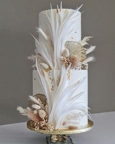 a white and gold wedding cake with feathers on it