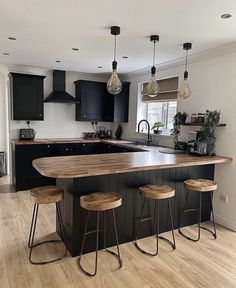 a kitchen with black cabinets and wooden stools next to an island in the middle