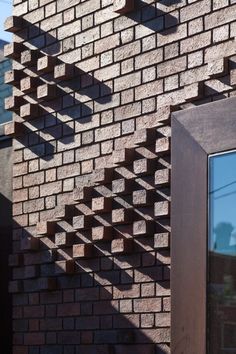 the shadow of a clock is cast on a brick building's face and wall