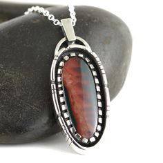 A beautiful Idaho Sunset Jasper Agate stone set in a Sterling Silver Necklace. This stunning jasper agate is a new and rare material mined in central Idaho with the most amazing color patterns. This stone loves being in the sunlight where the colors really pop and stand out the best. The colors can appear darker in shadier conditions. Pendant measures 2.5cm wide by 6.4cm long. Comes on an 18 inch sterling silver oval belcher chain. Includes gift box. Handmade by Annie Summers. We are husband and Agate Jewelry With Polished Finish For Gifts, Polished Agate Jewelry As A Gift, Agate Necklace With Polished Finish As A Gift, Oval Necklace With Inlay As Gift, Artisan Jasper Necklaces For Gift, Jasper Gemstone Jewelry As Gift, Jasper Jewelry For Gifts, Agate Necklace With Polished Finish For Gift, Oval Inlay Necklace Gift