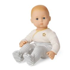 a baby doll sitting on the ground wearing striped pants and a white shirt with gold stars