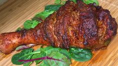 a piece of meat sitting on top of a wooden cutting board next to spinach leaves