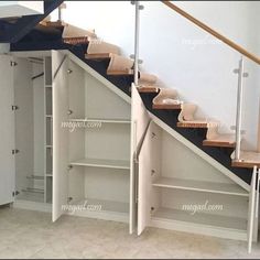 an open closet under the stairs in a room with white walls and carpeted flooring