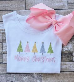 This adorable girl's shirt is perfect for Christmas and would be a super cute outfit for a Christmas card! The detailed design of the Christmas Trees, as well as the writing, is created by machine embroidery and uses high quality thread.  The white shirt is true to size and is made out of 100% combined cotton interlock fabric to keep your child completely comfortable. The shirt has naturally tapered shoulders and includes a ruffled hemline. The short sleeve shirts have puff sleeves.  Please chec Christmas Embroidery Gifts, Embroidery Shirt Ideas, Girly Christmas Shirts, Kids Christmas Embroidery Shirts, Embroidered Ideas, Pink Christmas Shirt, Kids Chrismtas Shirt, Machine Embroidery Gifts, Girls Christmas Shirts