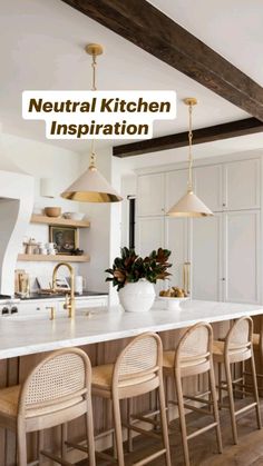 a large kitchen with white counter tops and gold pendant lights hanging from the ceiling over the island