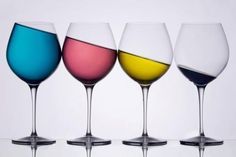 four wine glasses with different colored liquids in them