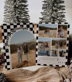 two christmas cards sitting on top of a table next to pine cones and fir trees