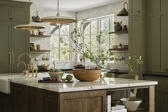 a kitchen with green cabinets and white counter tops, an island in the middle has a bowl on it