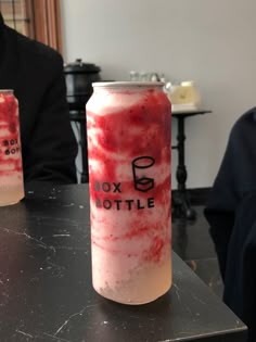 two red and white drinks sitting on top of a black table next to each other