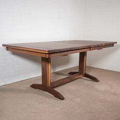 a large wooden table sitting in front of a white brick wall on concrete flooring