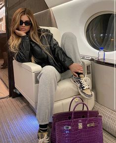 a woman sitting in a chair next to a purple purse