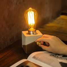 a person is lighting a light bulb on a book