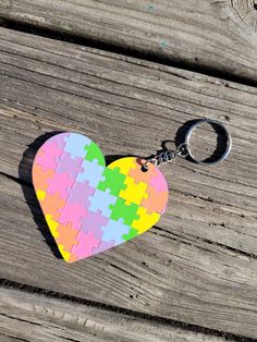 a heart shaped puzzle piece keychain sitting on top of a wooden table