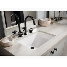 a bathroom sink with two faucets and soap dispensers on the counter