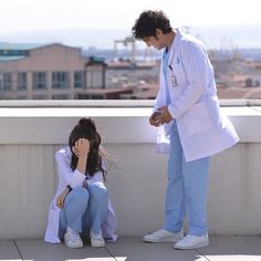 a man and woman sitting on a ledge next to each other