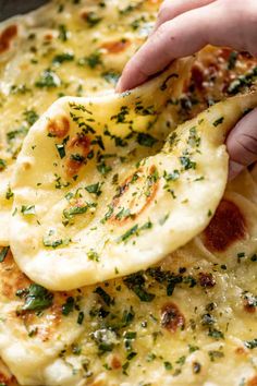 a person is dipping cheese on top of some pizza crusts with parmesan and chives