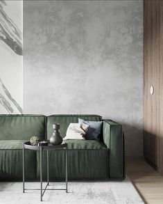 a green couch sitting in front of a gray wall