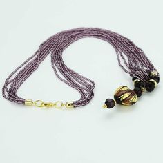 This gorgeous contemporary Murano necklace in rich amethyst and gold color palette features an exquisite 24K gold-layered heart at the center attached to a beautiful beaded ring and suspended from an elegant multi-strand beaded necklace. When this Venetian necklace captures the light you can really see it shine, as the seed beads and the heart light up with rich shades of amethyst, violet, and lilac reminding us of the treasures kept in Venice's decadent palazzos. This Murano glass necklace is a Elegant Crystal Necklaces With Polished Beads, Elegant Single Strand Crystal Necklace Gift, Elegant Round Crystal Necklaces With Polished Beads, Elegant Single Strand Pendant Crystal Necklace, Elegant Round Necklaces With Faceted Beads, Elegant Single Strand Crystal Necklace For Gift, Elegant Pendant Jewelry With Spacer Beads, Glass Pendant Necklace For Formal Occasions, Glass Pendant Necklaces For Formal Events