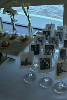 an arrangement of pictures and wine glasses on a table with flowers in vases next to them