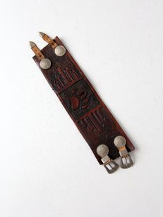 an old leather bookmark with metal buttons and screws attached to it on a white surface