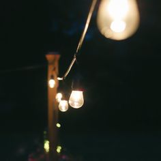 some lights hanging from a pole in the dark