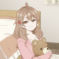 a woman holding a teddy bear while sitting on a bed