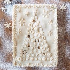 a decorated christmas tree made out of buttons on a table with snowflakes around it