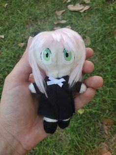 a hand holding a small doll with white hair and green eyes on it's face