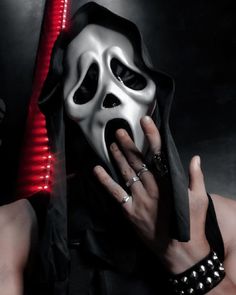 a woman wearing a white mask and black dress holding her hand up to her face