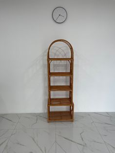 a wooden shelf sitting in front of a white wall with a clock on the wall