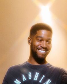 a man smiling and holding a cell phone in his right hand while wearing a t - shirt that says washington