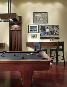 a pool table in a room with pictures on the wall