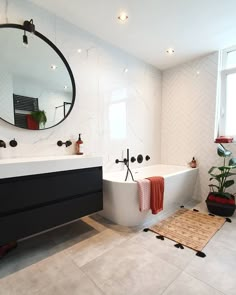 a bathroom with a white bathtub, sink and mirror on the wall next to a potted plant